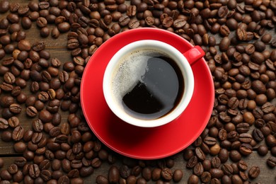 Photo of Aromatic coffee in cup and beans on wooden table, flat lay