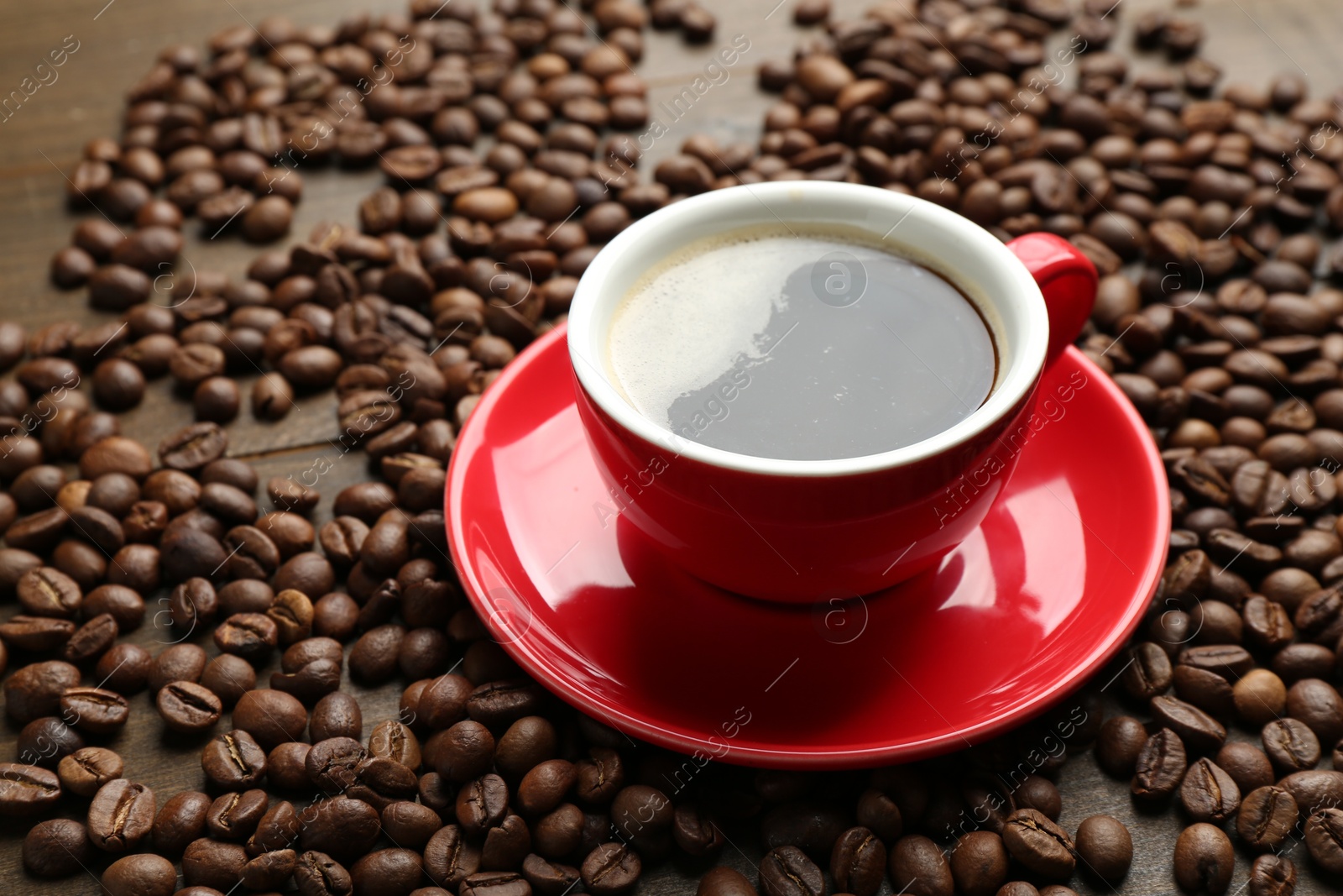 Aromatic coffee in cup and beans on wooden table, closeup Photo of Aromatic coffee in cup and beans on wooden table, closeup
