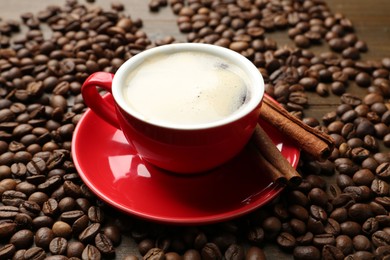 Photo of Aromatic coffee in cup, beans and cinnamon on table, closeup