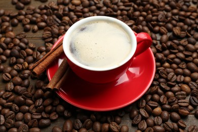 Photo of Aromatic coffee in cup, beans and cinnamon on table, above view