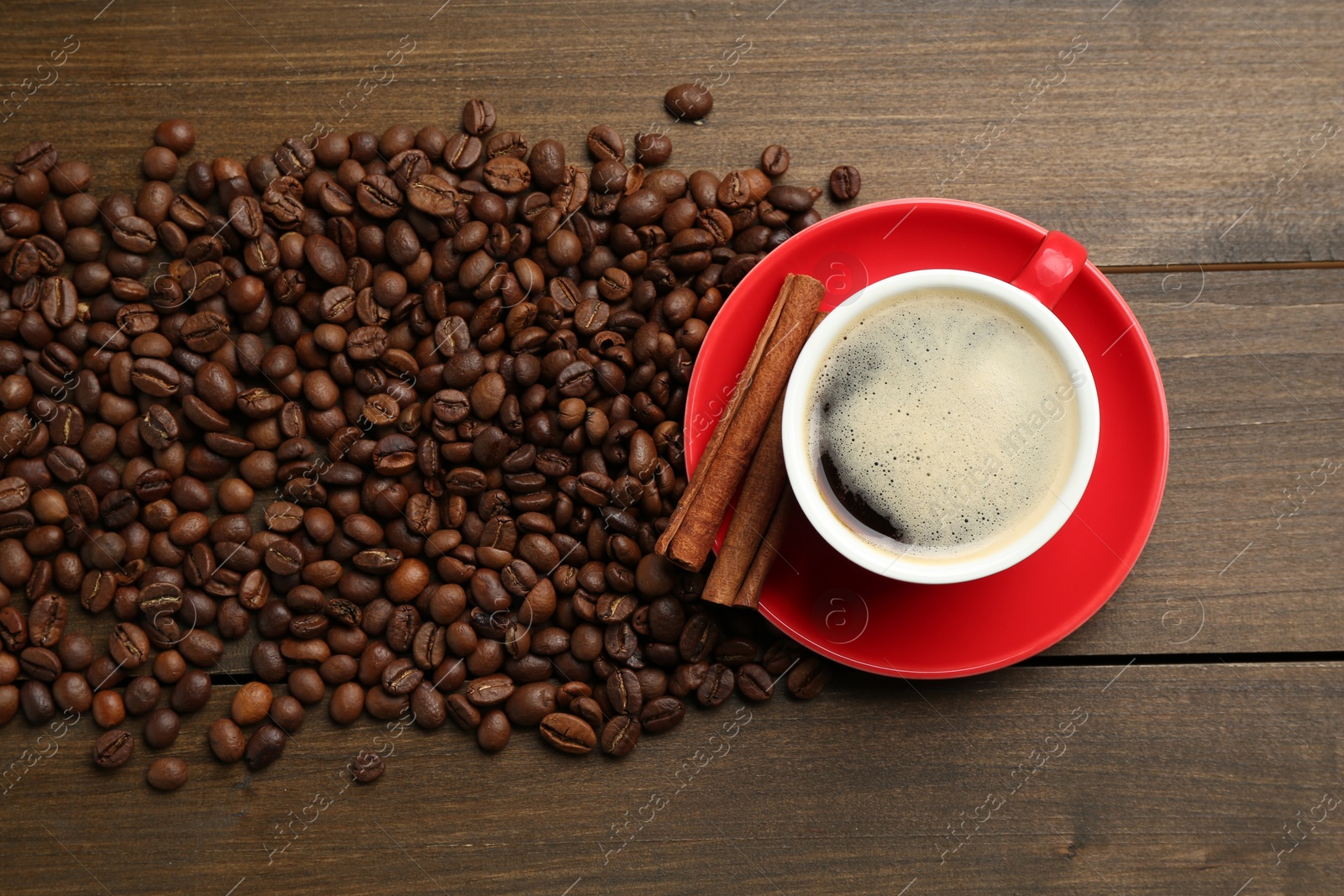 Aromatic coffee in cup, beans and cinnamon on wooden table, flat lay Photo of Aromatic coffee in cup, beans and cinnamon on wooden table, flat lay