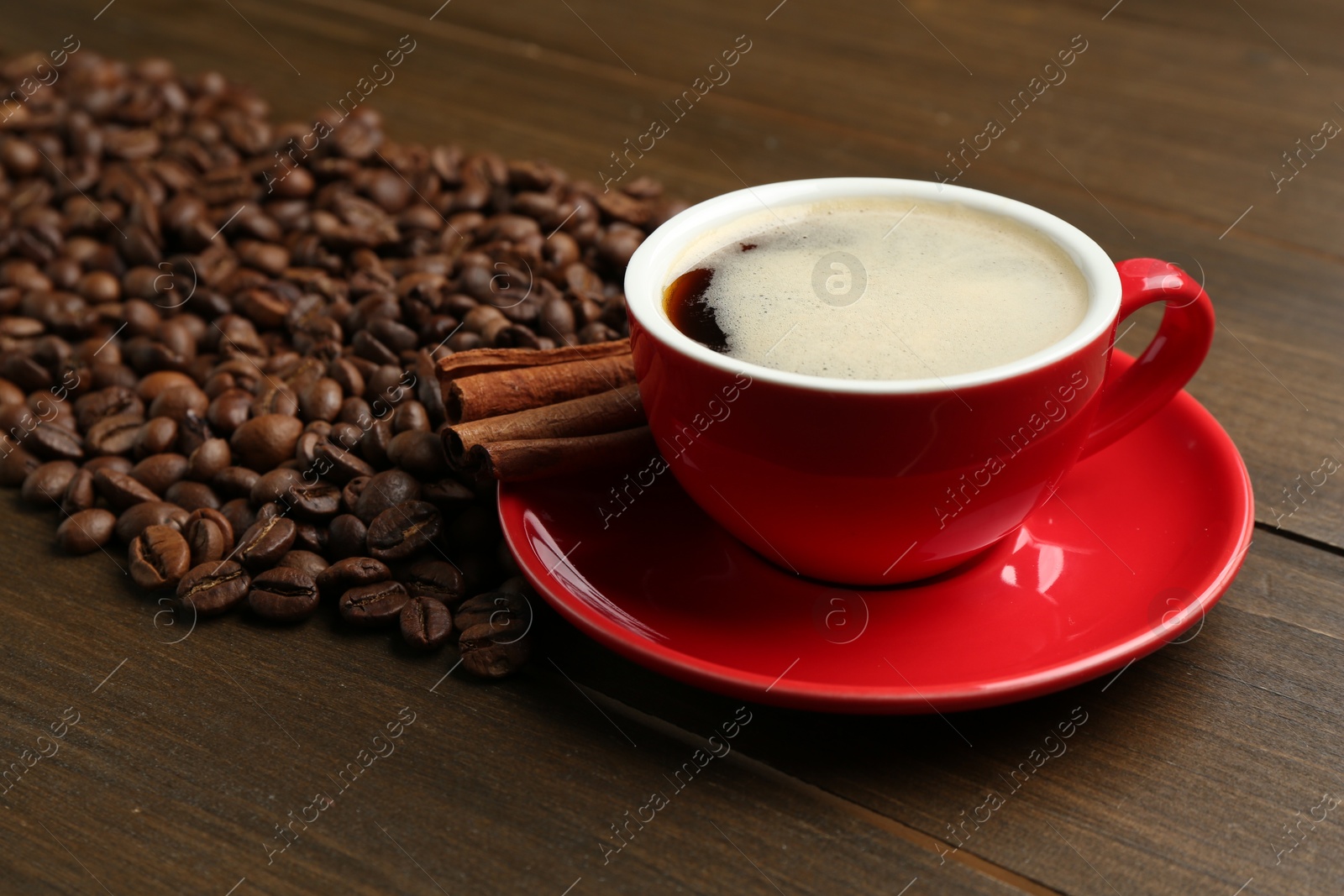 Aromatic coffee in cup, beans and cinnamon on wooden table, closeup Photo of Aromatic coffee in cup, beans and cinnamon on wooden table, closeup