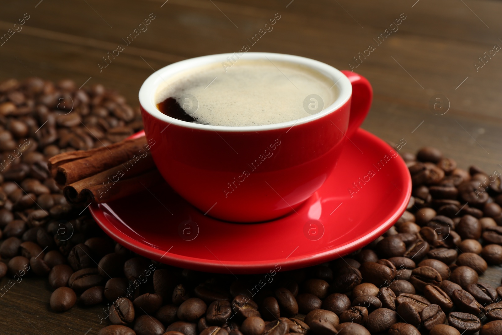 Aromatic coffee in cup, beans and cinnamon on wooden table, closeup Photo of Aromatic coffee in cup, beans and cinnamon on wooden table, closeup