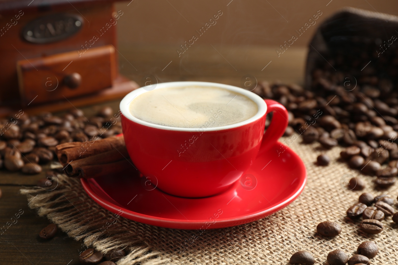 Aromatic coffee in cup, beans, cinnamon and grinder on wooden table, closeup Photo of Aromatic coffee in cup, beans, cinnamon and grinder on wooden table, closeup