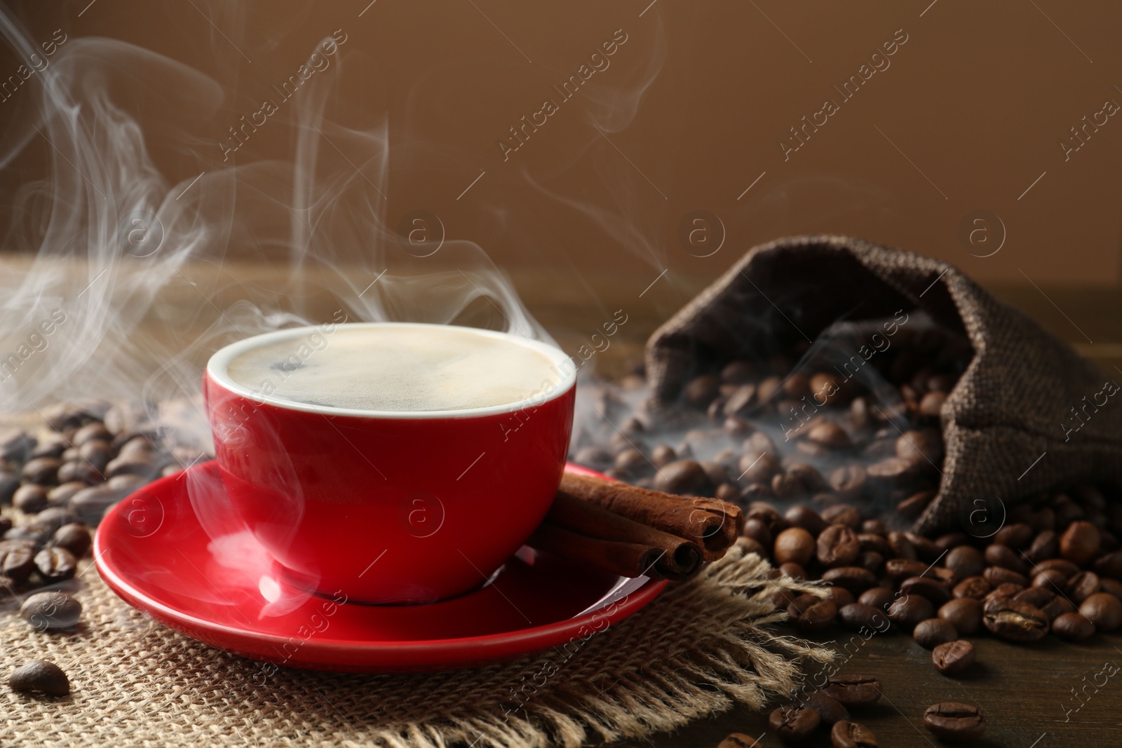 Aromatic coffee in cup, beans and cinnamon on wooden table, closeup Photo of Aromatic coffee in cup, beans and cinnamon on wooden table, closeup