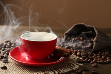 Photo of Aromatic coffee in cup, beans and cinnamon on wooden table, closeup