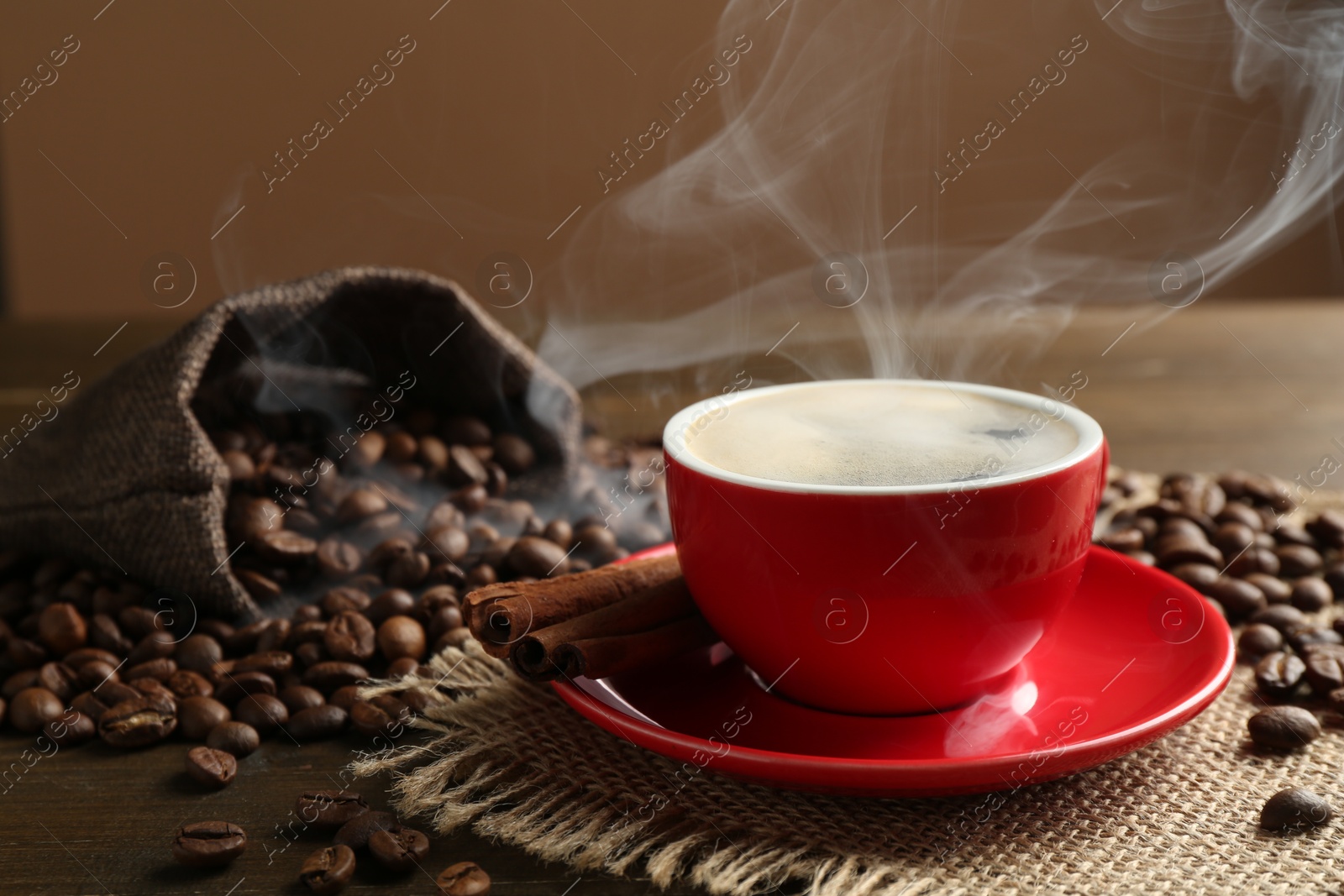 Aromatic coffee in cup, beans and cinnamon on wooden table, closeup Photo of Aromatic coffee in cup, beans and cinnamon on wooden table, closeup