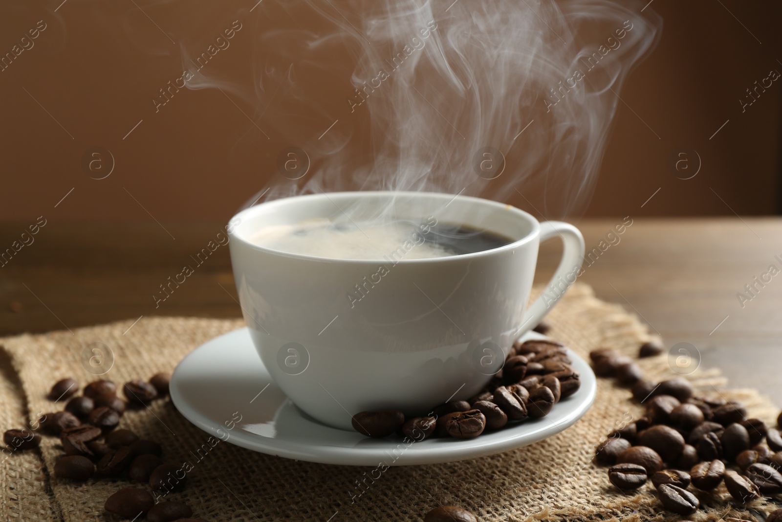 Aromatic coffee in cup and beans on table, closeup Photo of Aromatic coffee in cup and beans on table, closeup