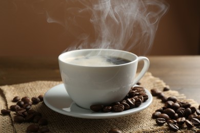 Photo of Aromatic coffee in cup and beans on table, closeup