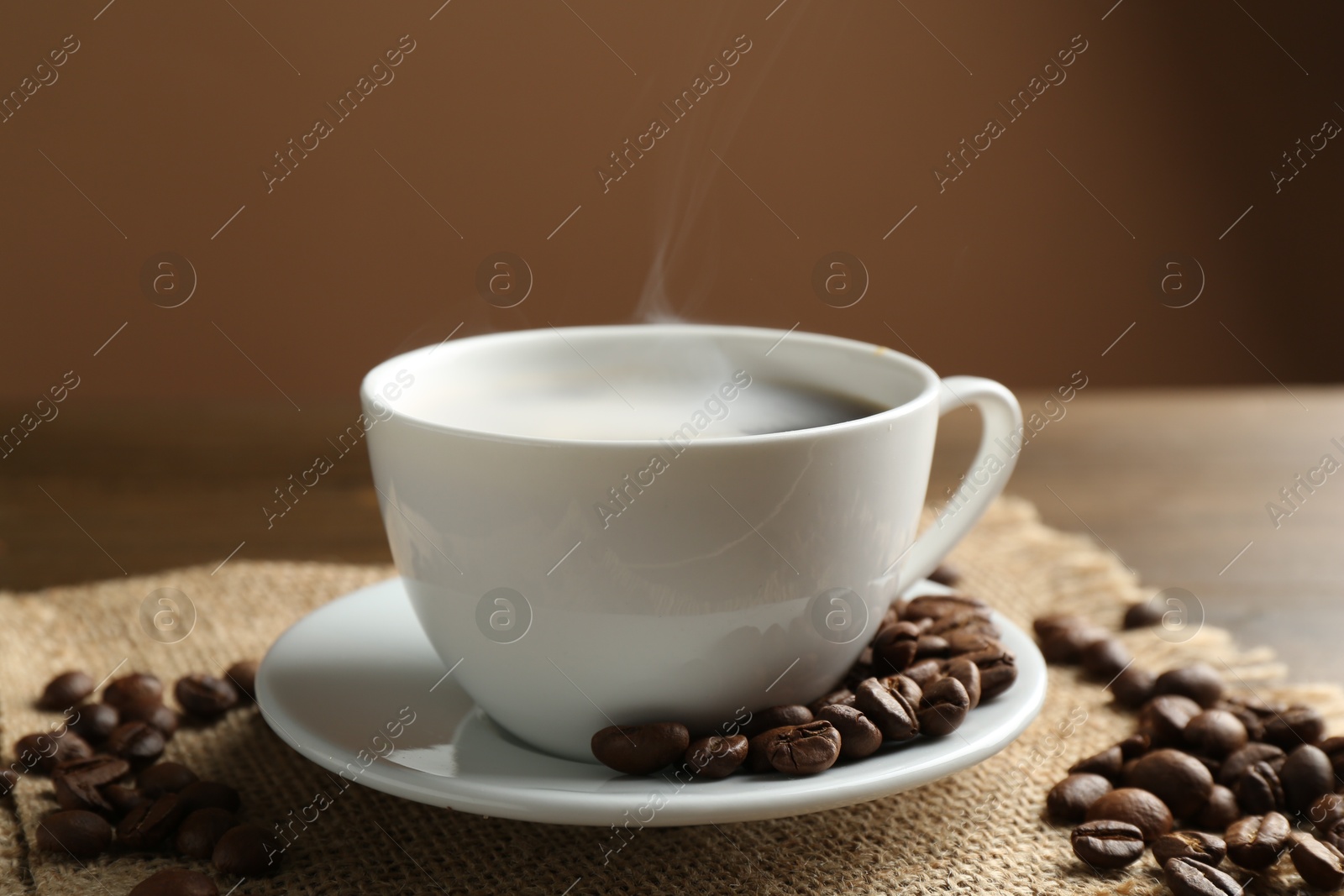 Aromatic coffee in cup and beans on table, closeup Photo of Aromatic coffee in cup and beans on table, closeup