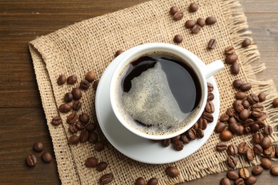 Photo of Aromatic coffee in cup and beans on wooden table, flat lay