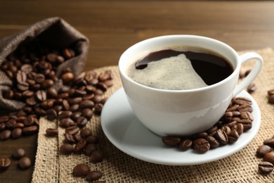 Photo of Aromatic coffee in cup and beans on table, closeup