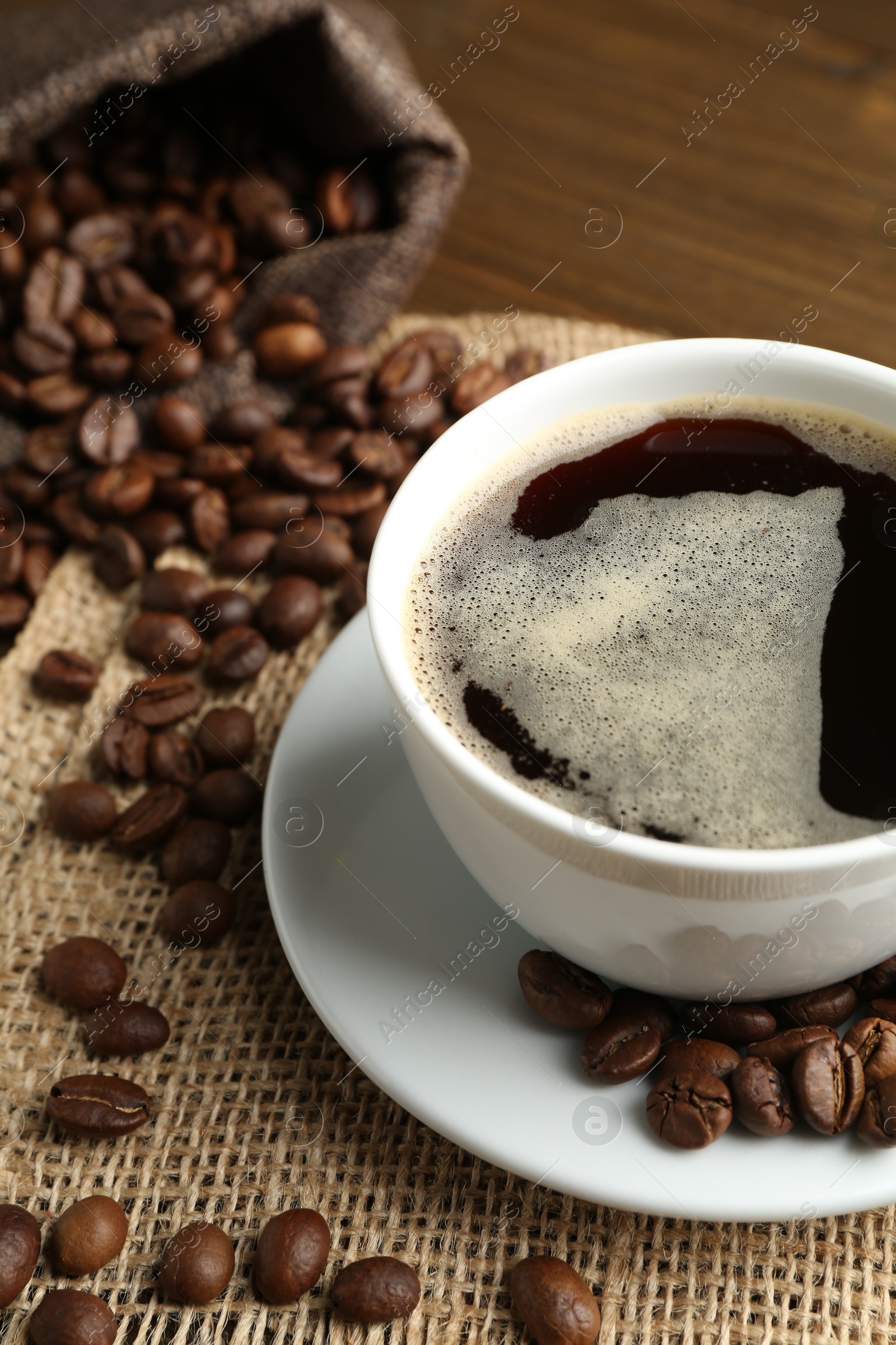 Aromatic coffee in cup and beans on table, closeup Photo of Aromatic coffee in cup and beans on table, closeup