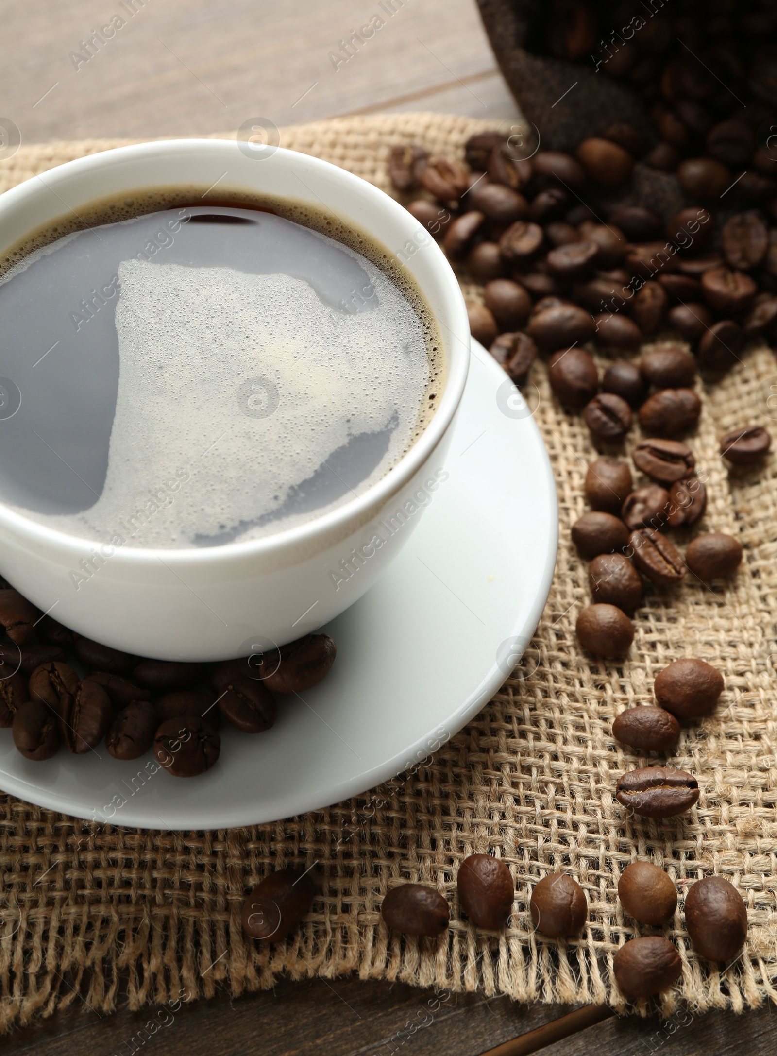 Aromatic coffee in cup and beans on wooden table, above view Photo of Aromatic coffee in cup and beans on wooden table, above view