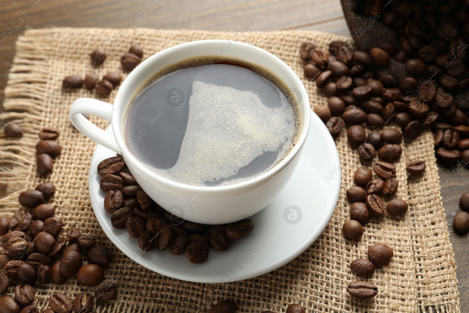 Aromatic coffee in cup and beans on table, above view Photo of Aromatic coffee in cup and beans on table, above view