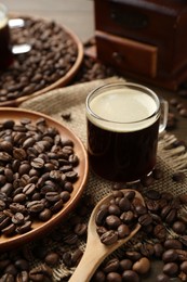 Photo of Aromatic coffee in cup and beans on table, closeup
