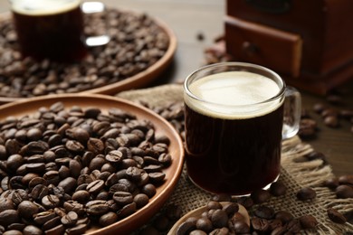 Photo of Aromatic coffee in cup and beans on table, closeup