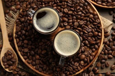 Photo of Aromatic coffee in cups and beans on table, flat lay