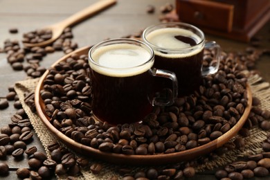 Photo of Aromatic coffee in cups and beans on wooden table, closeup