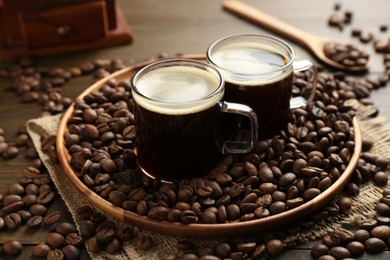 Photo of Aromatic coffee in cups and beans on wooden table, closeup