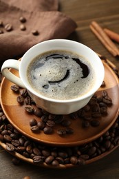 Photo of Aromatic coffee in cup, beans and cinnamon on table, closeup