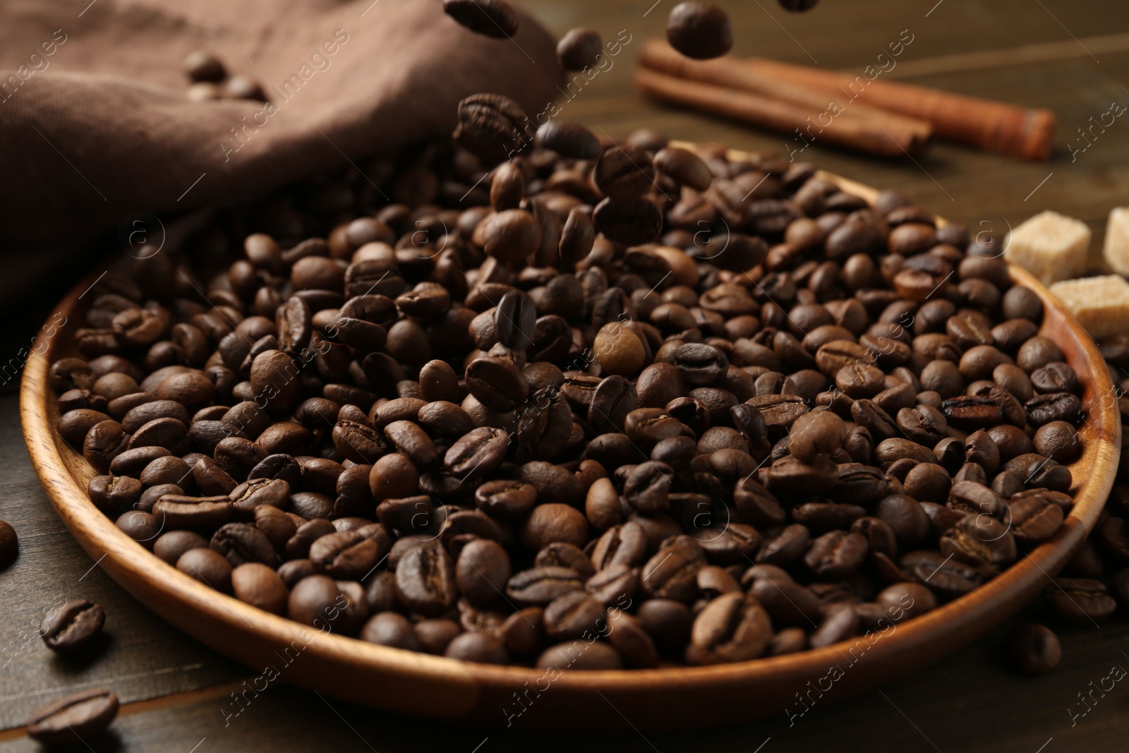 Pouring coffee beans onto plate at table, closeup Photo of Pouring coffee beans onto plate at table, closeup