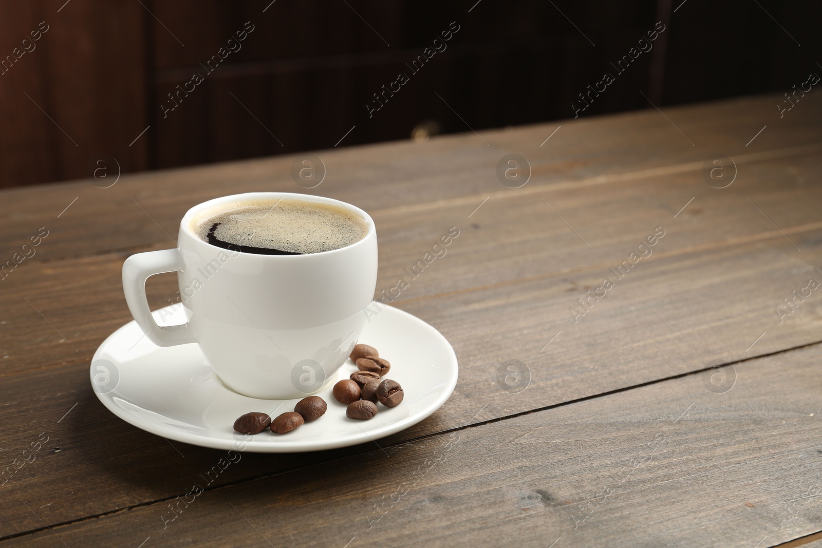 Aromatic coffee in cup and beans on wooden table, closeup. Space for text Photo of Aromatic coffee in cup and beans on wooden table, closeup. Space for text