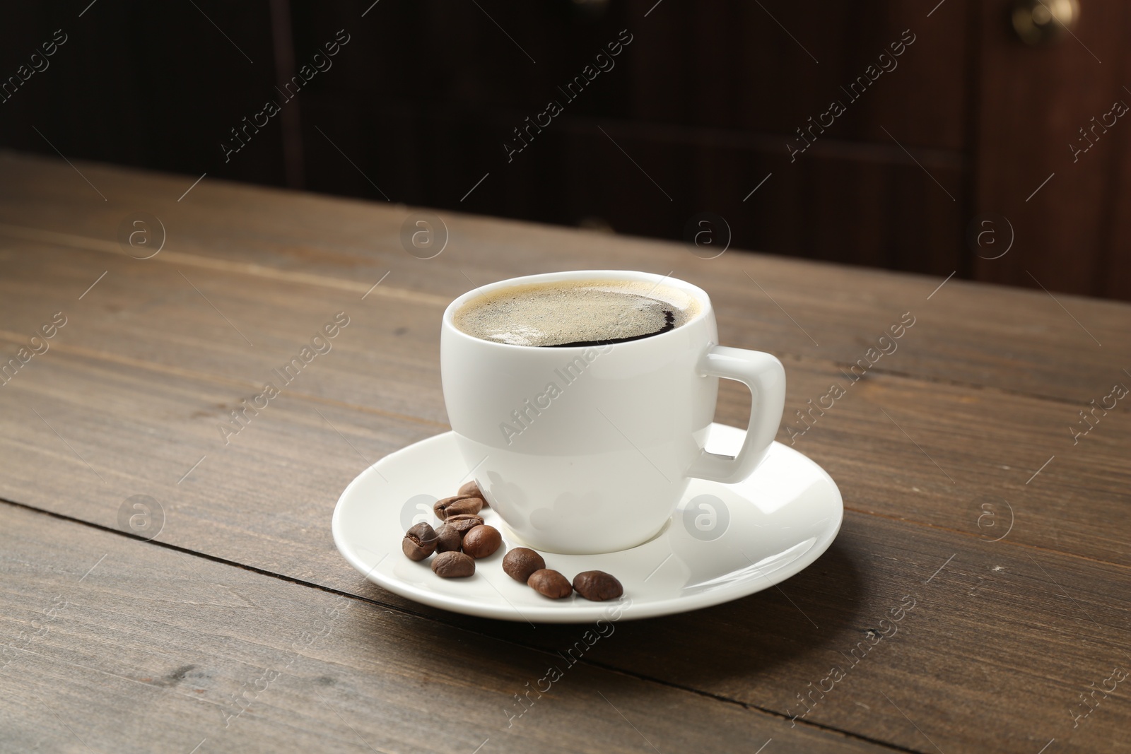 Aromatic coffee in cup and beans on wooden table, closeup Photo of Aromatic coffee in cup and beans on wooden table, closeup
