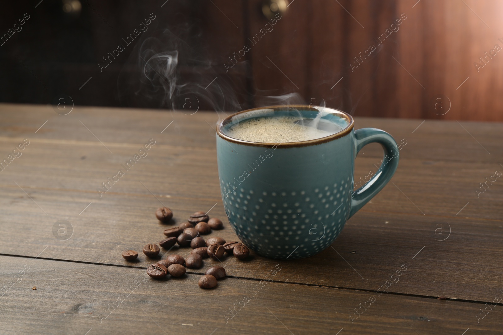 Aromatic coffee in cup and beans on wooden table Photo of Aromatic coffee in cup and beans on wooden table