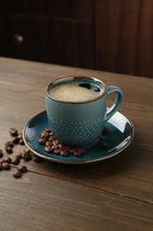 Photo of Aromatic coffee in cup and beans on wooden table, closeup