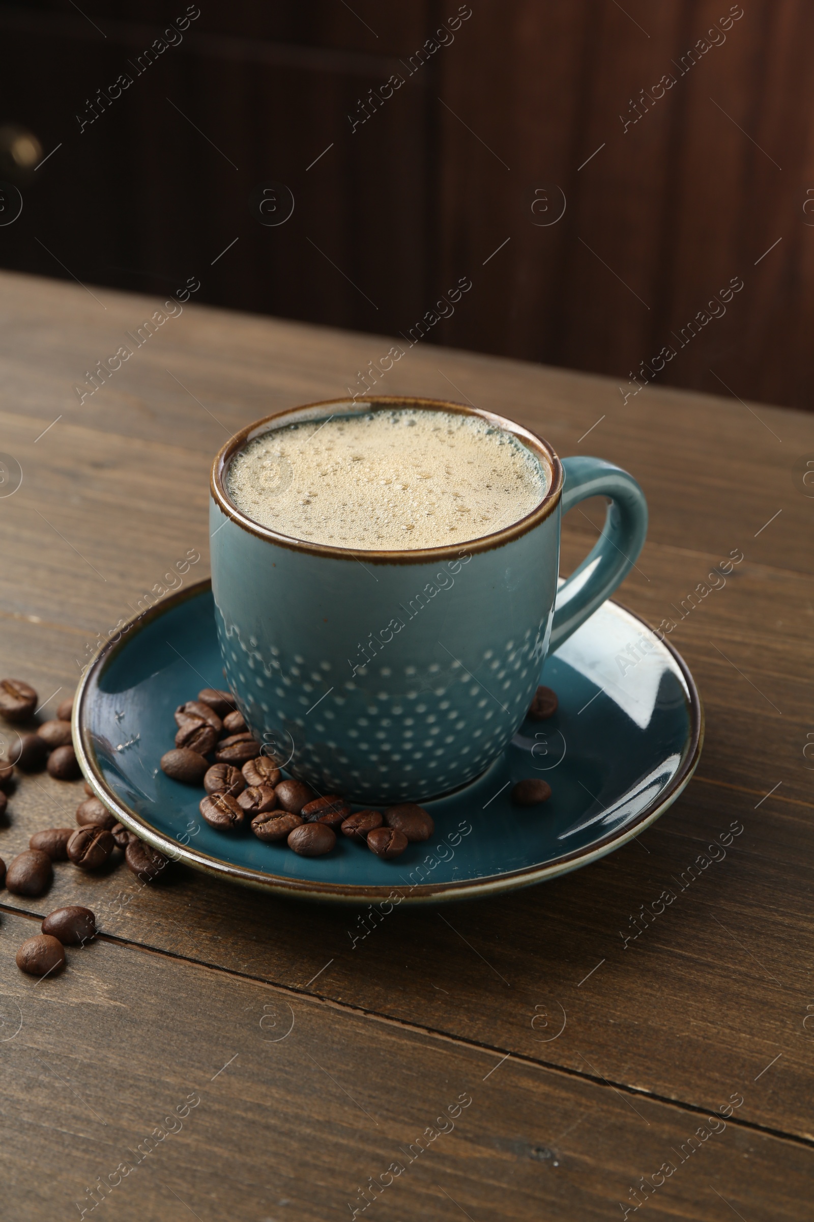 Aromatic coffee in cup and beans on wooden table, closeup Photo of Aromatic coffee in cup and beans on wooden table, closeup