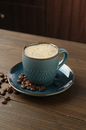 Photo of Aromatic coffee in cup and beans on wooden table, closeup