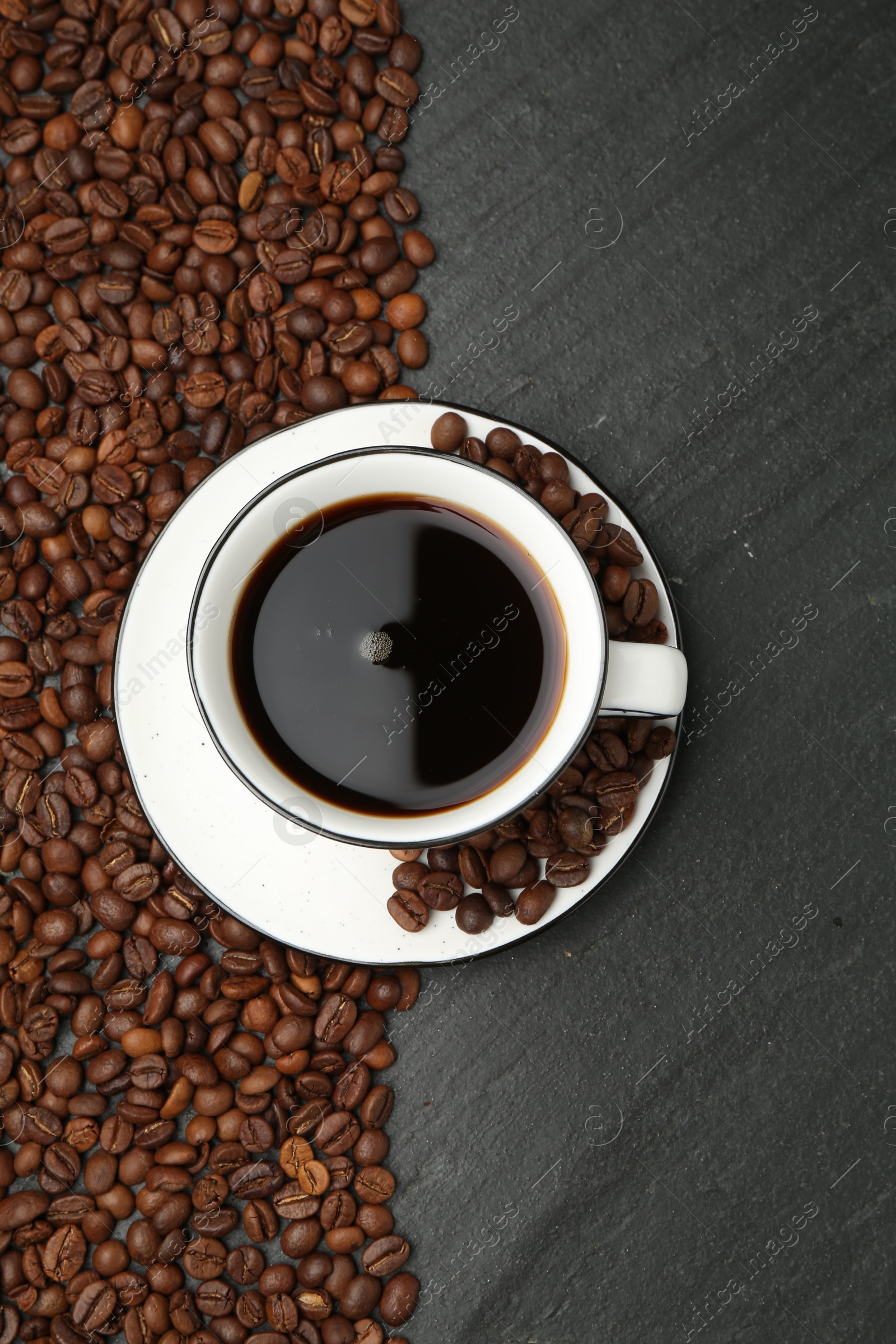 Aromatic coffee in cup and beans on black table, flat lay Photo of Aromatic coffee in cup and beans on black table, flat lay
