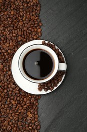 Photo of Aromatic coffee in cup and beans on black table, flat lay