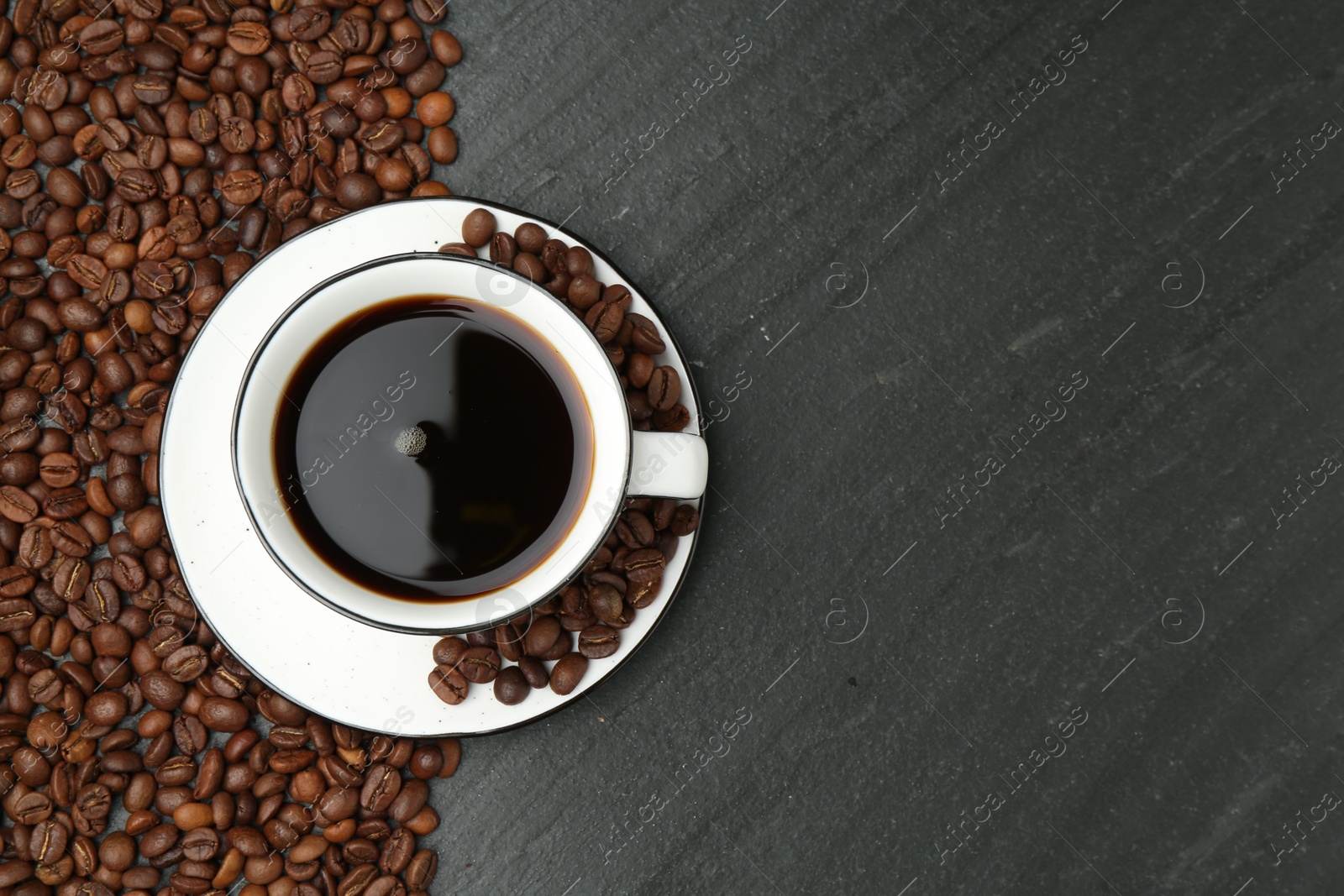 Aromatic coffee in cup and beans on black table, flat lay. Space for text Photo of Aromatic coffee in cup and beans on black table, flat lay. Space for text