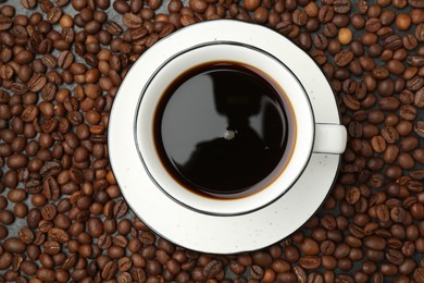 Photo of Aromatic coffee in cup on beans, top view