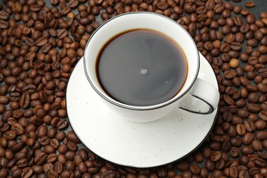 Photo of Aromatic coffee in cup on beans, above view