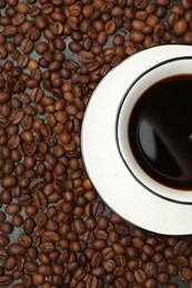 Photo of Aromatic coffee in cup on beans, top view