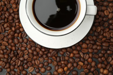 Photo of Aromatic coffee in cup on beans, top view