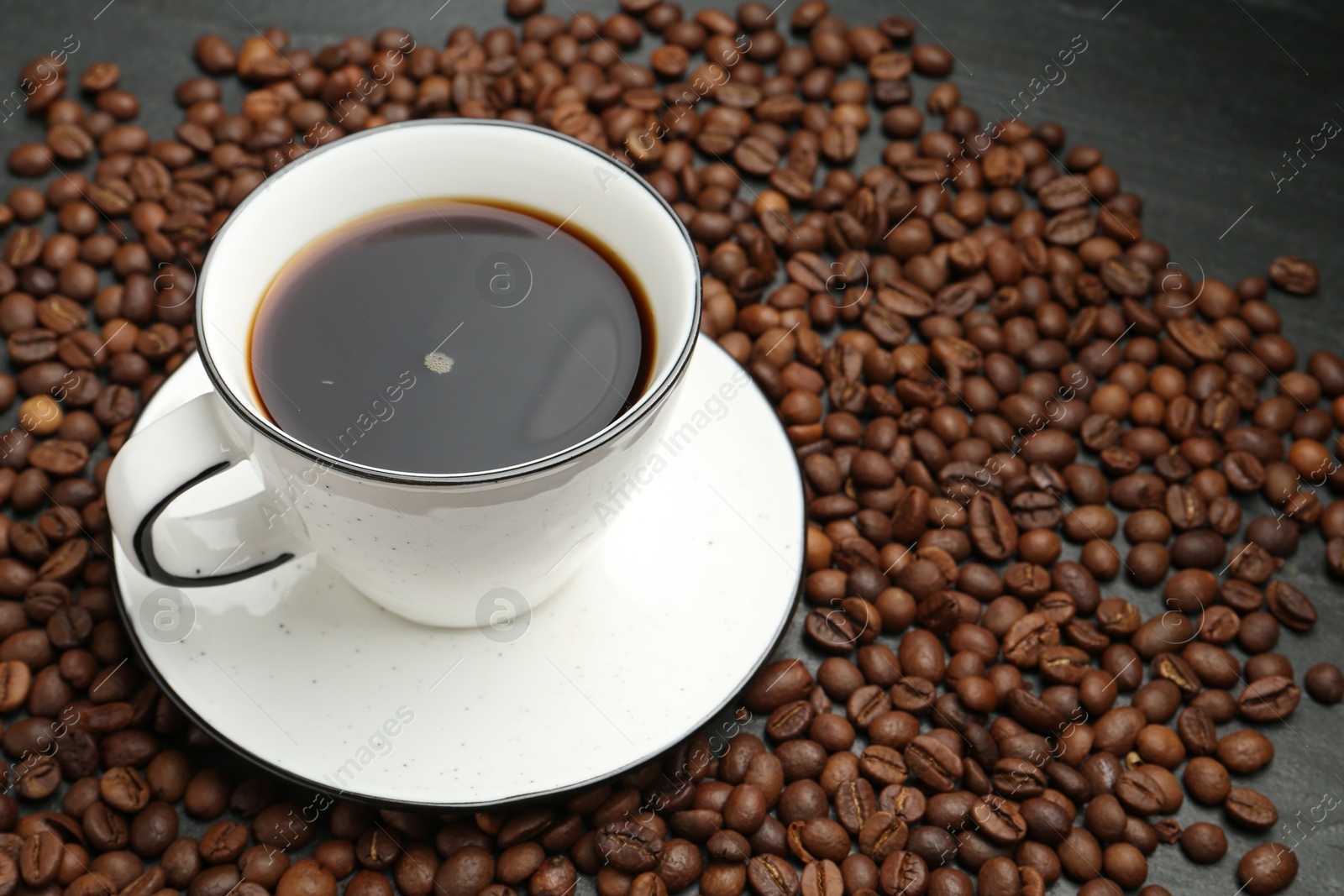 Aromatic coffee in cup and beans on black table, closeup. Space for text Photo of Aromatic coffee in cup and beans on black table, closeup. Space for text