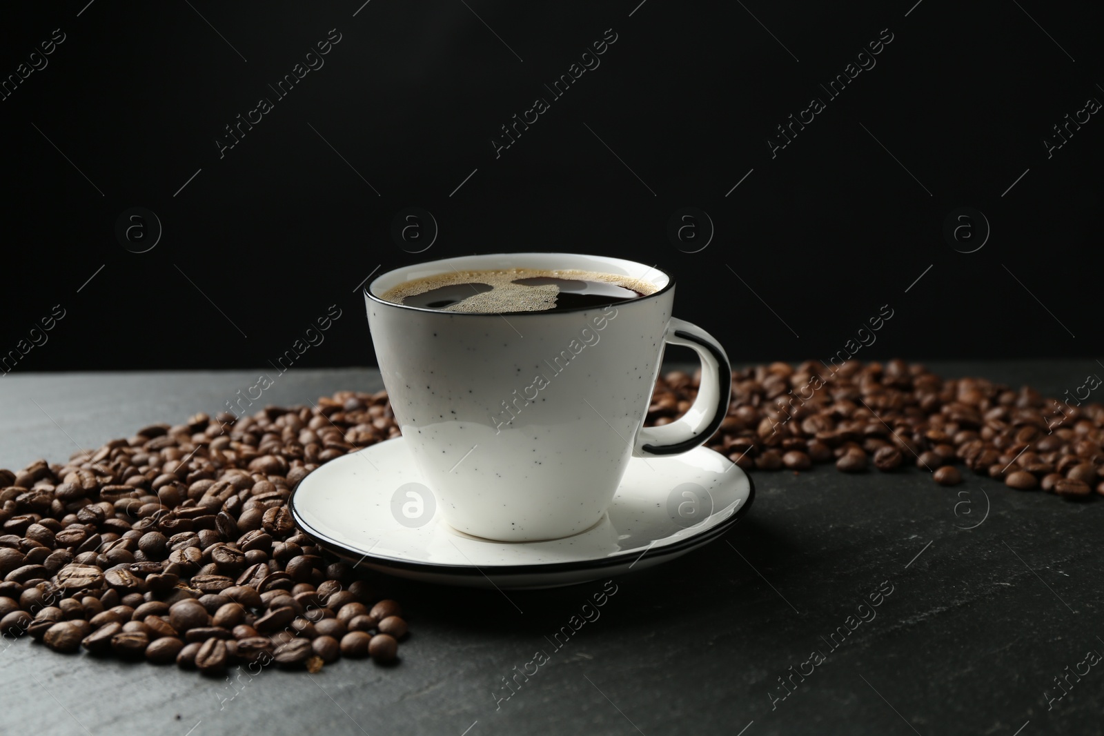 Aromatic coffee in cup and beans on black table, closeup Photo of Aromatic coffee in cup and beans on black table, closeup