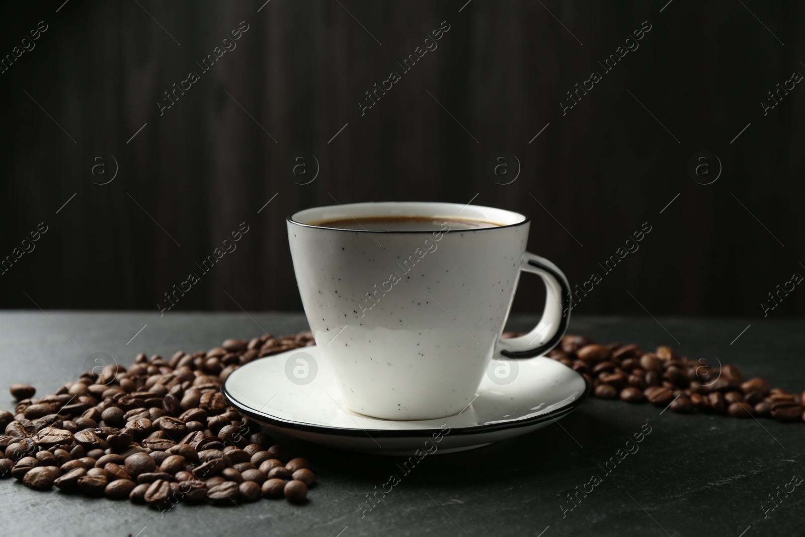 Aromatic coffee in cup and beans on black table, closeup Photo of Aromatic coffee in cup and beans on black table, closeup