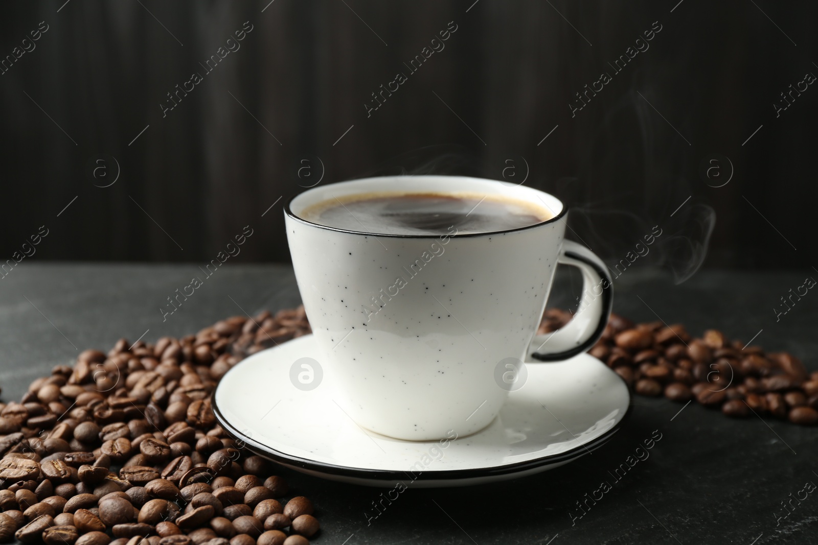 Aromatic coffee in cup and beans on black table, closeup Photo of Aromatic coffee in cup and beans on black table, closeup