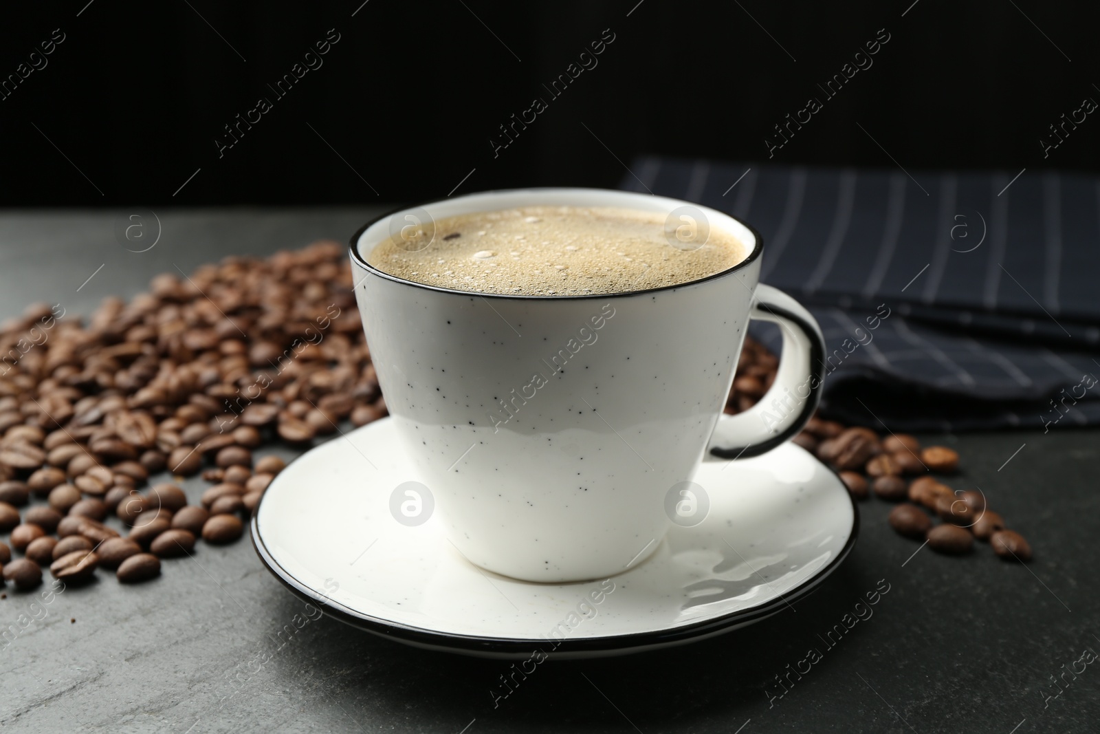 Aromatic coffee in cup and beans on black table, closeup Photo of Aromatic coffee in cup and beans on black table, closeup