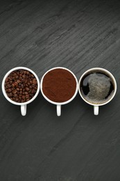 Photo of Aromatic ground coffee, beans and hot drink on black table, flat lay