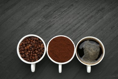 Photo of Aromatic ground coffee, beans and hot drink on black table, flat lay. Space for text