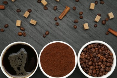 Photo of Cup of drink, ground coffee, beans, brown sugar and cinnamon on black table, flat lay