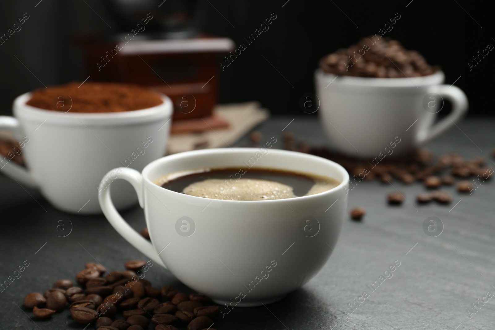 Cup of drink, ground coffee and beans on black table, closeup Photo of Cup of drink, ground coffee and beans on black table, closeup