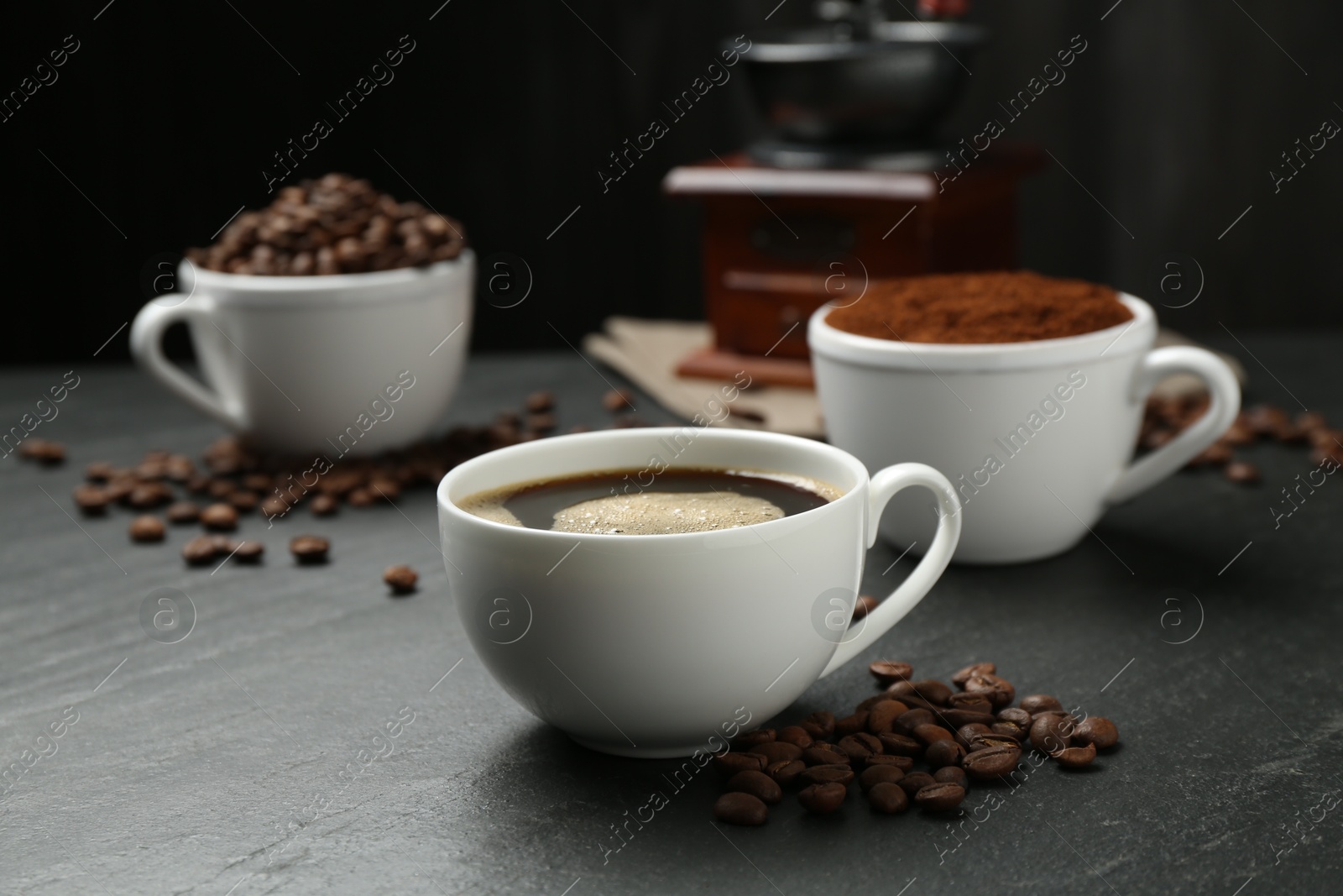 Cup of drink, ground coffee and beans on black table, closeup Photo of Cup of drink, ground coffee and beans on black table, closeup