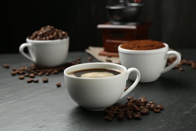 Photo of Cup of drink, ground coffee and beans on black table, closeup